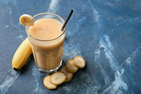 Glass of healthy banana smoothie on color backgroundの写真素材