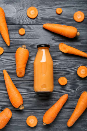 Bottle of healthy carrot smoothie on dark wooden backgroundの写真素材