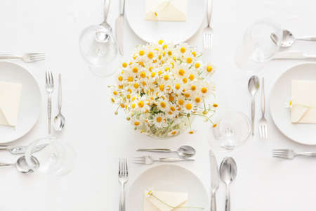 Stylish table setting and chamomile flowers on light backgroundの写真素材