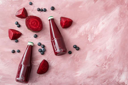 Bottles of healthy smoothie with beetroots and blueberries on color background