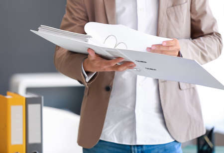 Young man with open folder in office, closeup