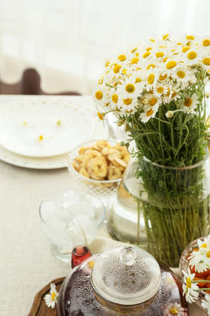 Stylish table setting and vase with chamomile flowers on light background, closeup