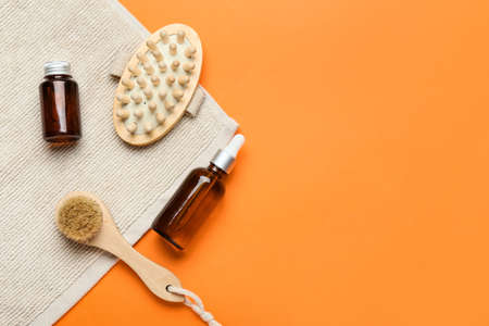 Massage brushes and bottles of cosmetic products on color backgroundの写真素材