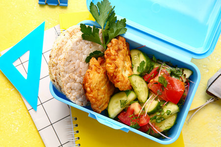 Lunch box with tasty food and school stationery on color background