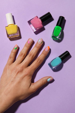 Female hand and nail polishes on color backgroundの写真素材