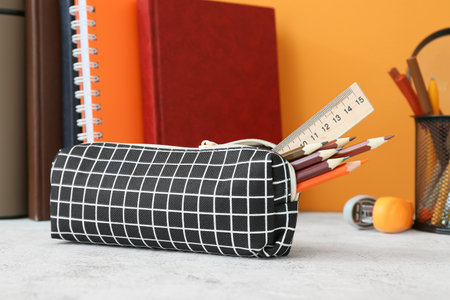 Pencil case and stationery on color background