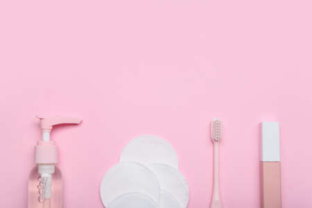 Bottle of cosmetic product, cotton pads, toothbrush and lipstick on pink backgroundの写真素材