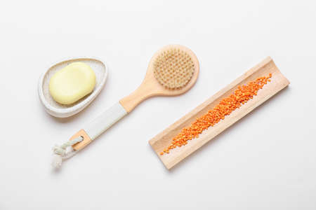 Massage brush and different bath supplies on gray background