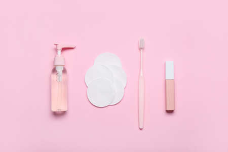 Bottle of cosmetic product, cotton pads, toothbrush and lipstick on color backgroundの写真素材