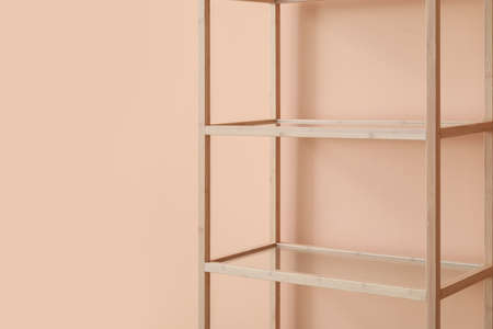 Empty wooden shelving unit near pink wallの写真素材