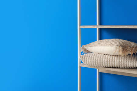 Shelving unit with pillows near blue wall