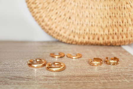 Stylish golden earrings on wooden shelf in room, closeupの写真素材