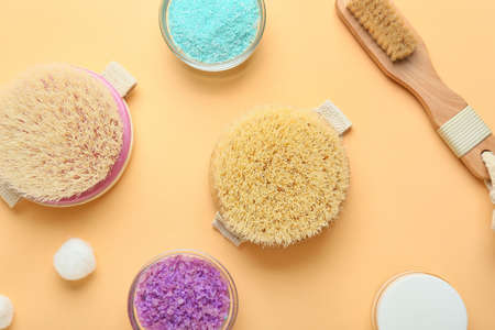 Different massage brushes and bath supplies on color background
