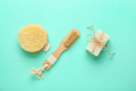 Different massage brushes and soap on color background