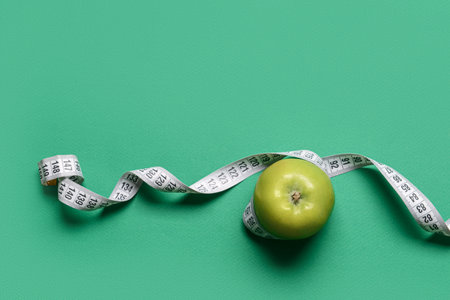 Green apple with measuring tape on color backgroundの写真素材