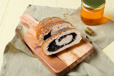 Wooden board with tasty cut poppy seeds bun on color wooden backgroundの写真素材