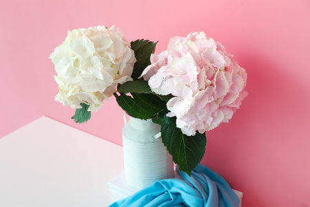 Vase with beautiful hydrangea flowers on shelf near color wall