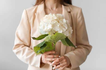 Young woman with hydrangea flowers on light backgroundの写真素材