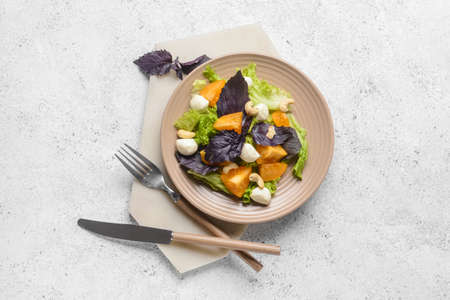 Plate with tasty fresh salad on light backgroundの写真素材