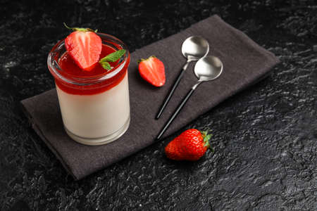 Glass with tasty strawberry panna cotta on black backgroundの写真素材