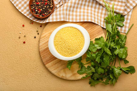 Bowl of raw couscous with parsley on color backgroundの写真素材