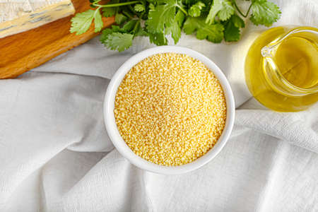 Bowl of raw couscous and oil on tableの写真素材