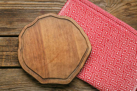 Board with napkin on wooden background