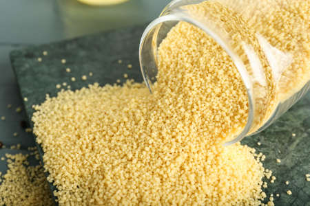 Jar with raw couscous on table, closeup