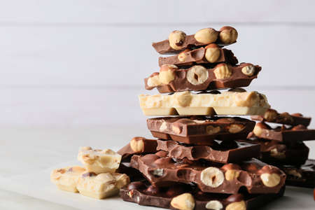 Pieces of tasty chocolate with nuts on light backgroundの写真素材