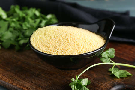 Bowl of raw couscous with parsley on tableの写真素材