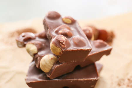 Pieces of tasty chocolate with hazelnuts on table, closeupの写真素材