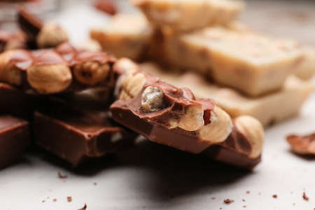 Pieces of tasty chocolate with hazelnuts on table, closeupの写真素材
