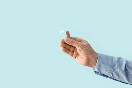 Male hand with hearing aid on color backgroundの写真素材