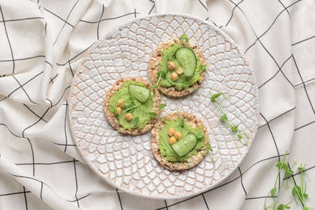 Plate with crispbreads and tasty pea hummus on table
