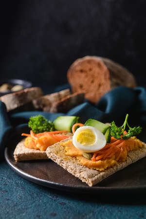 Plate with crispbreads and tasty hummus on dark backgroundの写真素材