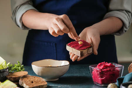 Woman making tasty sandwich with healthy hummus at tableの写真素材