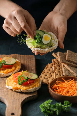 Woman making tasty sandwich with healthy hummus at tableの写真素材