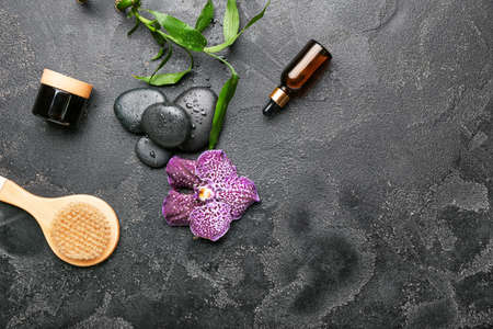 Spa composition with massage brush and cosmetics on dark background