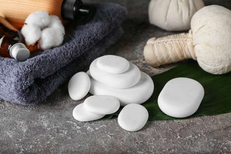 Spa stones with bathing towel, cosmetics and herbal bag on grunge background