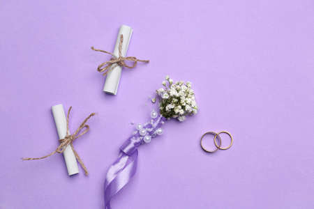 Beautiful gypsophila boutonniere, wedding rings and invitations on color backgroundの写真素材