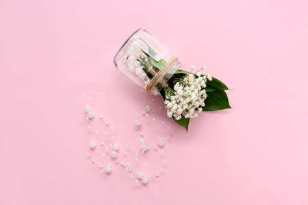 Jar with beautiful gypsophila boutonnieres and beads on color backgroundの写真素材
