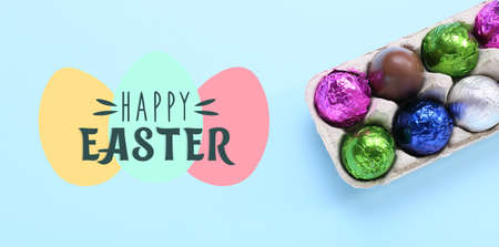 Chocolate eggs and text HAPPY EASTER on light blue background