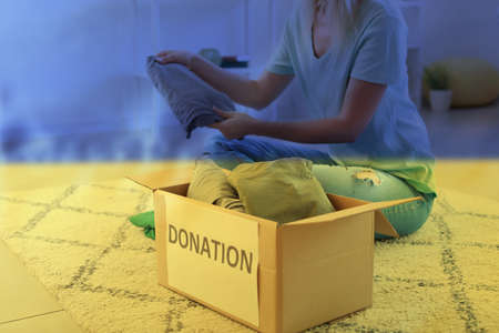 Double exposure of volunteer female putting clothes in donation box and flag of Ukraine. Humanitarian aid for refugeesの写真素材