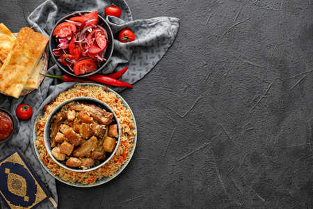 Tasty Asian pilaf with vegetable salad and flatbread on dark backgroundの写真素材