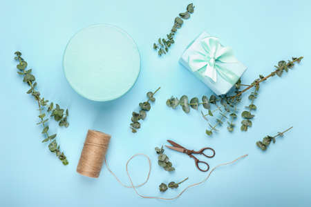 Composition with gift boxes, scissors, rope and eucalyptus branches on color backgroundの写真素材