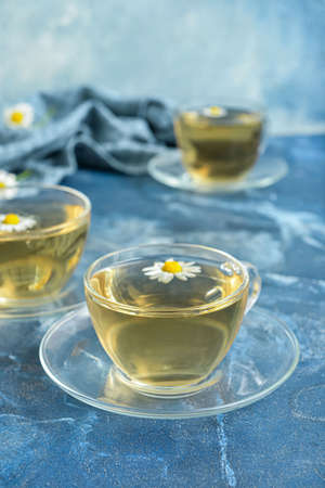 Cups of floral tea with chamomile flowers on color backgroundの写真素材