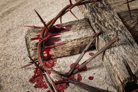 Crown of thorns, wooden cross, nails and blood drops on sand. Jesus Christ's sacrifice and atonement of our sinsの写真素材