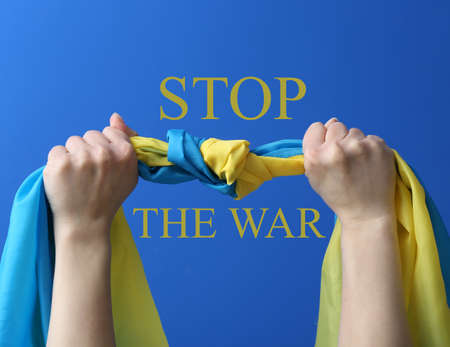 Hands with flag of Ukraine and text STOP THE WAR on blue backgroundの写真素材