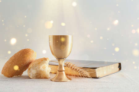 Chalice of wine with bread and Bible on light background. Holy Communion concept