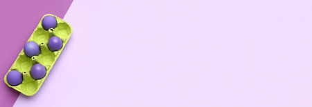 Holder with painted Easter eggs on lilac background with space for textの写真素材